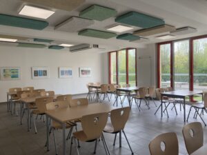 Essensbereich mit großen Fenstern und bunten Bildern an der Wand.