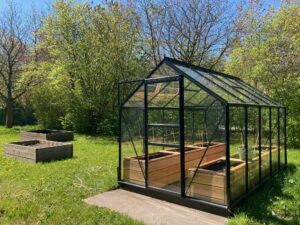 Gewächshaus und freistehende Beete auf Wiese